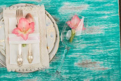 Tableware and silverware with light pink gladiolus on the azure background Stock Photos