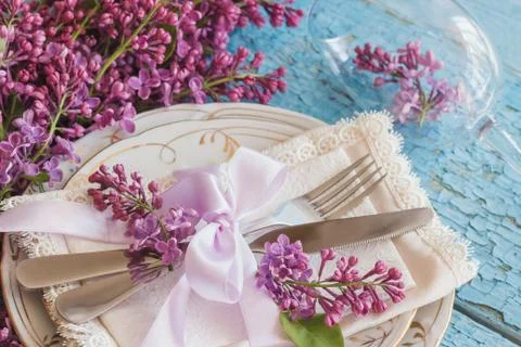 Tableware and silverware with violet lilac on the wooden background 库存照片