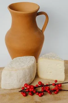 Tableware clay pitcher, cheese, berries on wooden table Stock Photos