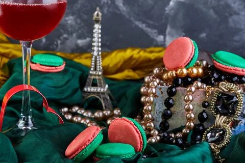 Tableware, stemware, and a necklace laid out with macarons and a glass of wine Stock Photos