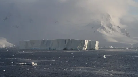 Tabular iceberg with mountains in background Stock Footage