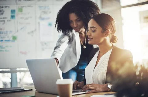Tackling a new task together. two businesswomen working together on a laptop in Stock Photos