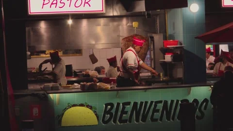 Taco chef making al pastor tacos under "al pastor" sign during CDMX food night Stock Footage 318723794