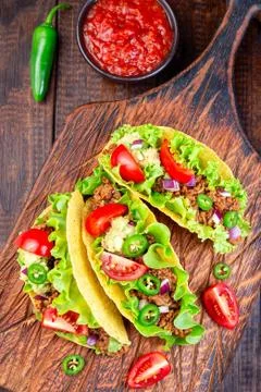 Taco shells with lettuce, ground beef meat,  mashed avocado, tomato 스톡 사진