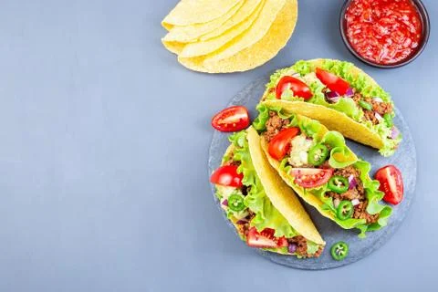Taco shells on a stone plate, with lettuce, ground beef meat,  mashed avocado Foto stock