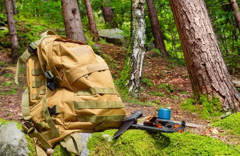 Tactical backpack with flashlight and knife laying on forest rocks. Foto stock