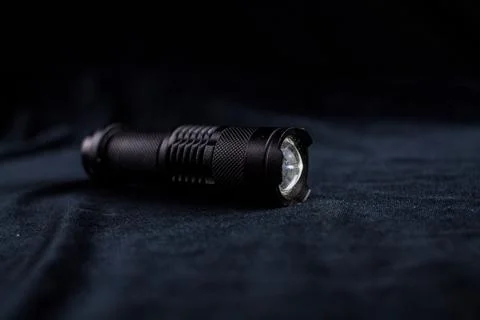 Tactical flashlight on a black background shines Stock-Fotos