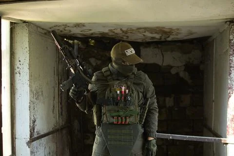 A tactical operator in full military gear stands in an abandoned building. Stock Photos