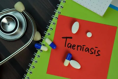 Taeniasis write on sticky notes isolated on Wooden Table. Stock Photos