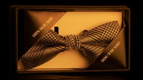 Tagged luxurious patterned silk bow tie in retail box - golden light 4k Stock Footage 98402524