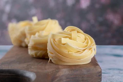 Tagliatelle in a spoon on the kitchen table. Stock Photos