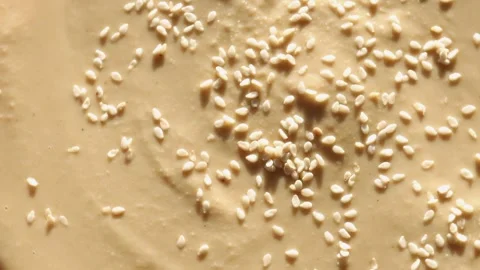 Tahini paste rotates in circle, highlighting its creamy blend of sesame seeds Stock Footage 295149336