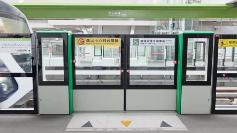 Taichung MRT boarding through screen doors at Zhongqing Station with train Stock Footage 334576412