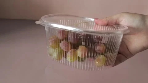 Taifi grapes in plastic container in a womans hand close-up. Storing berries at Stock Footage 324770046