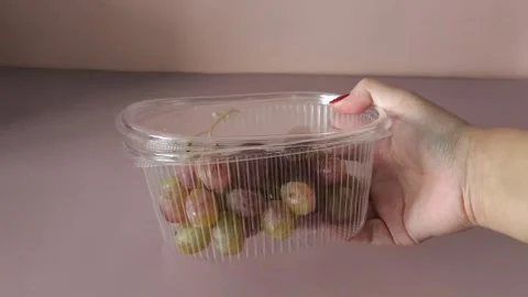 Taifi grapes in plastic container in a womans hand close-up. Storing berries at Stock Footage 324770056