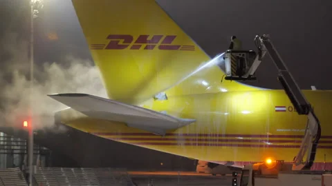 Tail and Elevator of DHL Freighter Airplane Getting De-icing Treatment Stock Footage 230883499