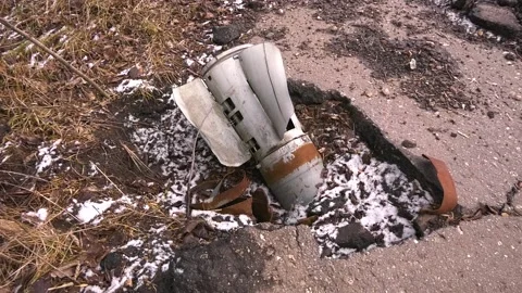 The tail of the shell sticks out of the asphalt. The shell hit the road in the Stock Footage 235628038