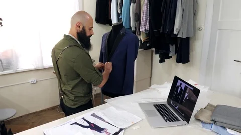 Tailor adjusting fabrics on a tailored mannequin.Tailor uses laptop. Stock Footage 80734883