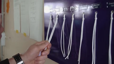 Tailor chooses parachute laces hanging on stand at plant Stock Footage 236908041