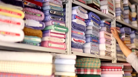 Tailor choosing a light blue fabric in a fabric warehouse. Stock Footage