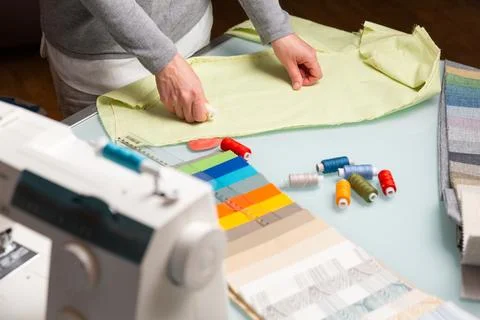 Tailor choosing right color of a thread using fabric samples on table durin.. Stock Photos