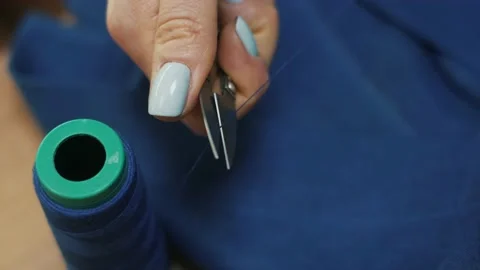 The tailor cuts the blue thread. Close-up. Vídeo Stock 152954017