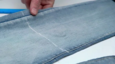 Tailor cuts leg of jeans with scissors for shortening and making summer shorts. Stock Footage 197376116