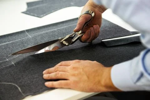 Tailor cutting fabric with large scissors Stock Photos