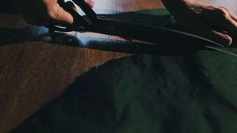 Tailor cutting fabric using large scissors or shears as he follows the chalk Stock-Footage 86450283