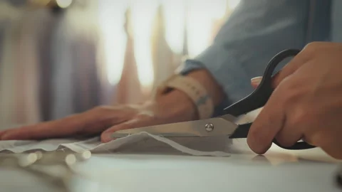 Tailor cutting fabric at a workstation during daylight in a sewing studio Stock Footage 331287930