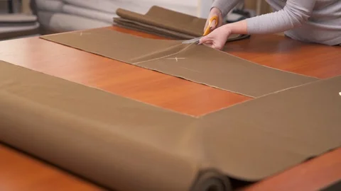 A tailor cutting a high quality brown material using professional scissors and Stock Footage 105491752
