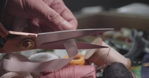 Tailor Cutting Pink Ribbon with Scissors During Garment Finishing Stock Footage 341936564