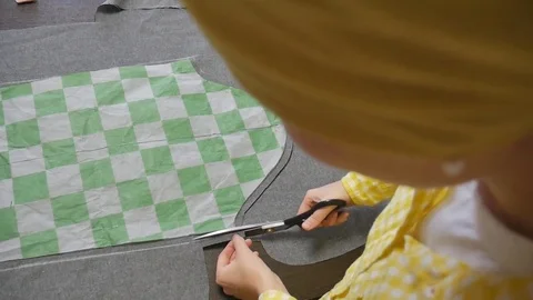 The tailor is cutting with scissors along the line of pattern. Stock Footage 79904639
