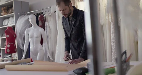 The tailor cutting a tissue curve on a desktop in dress atelier Video stock 129028807