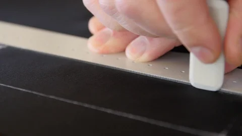 Tailor drawing lines on a black acetate lining with his chalk in order to make a Stock Footage 127471396