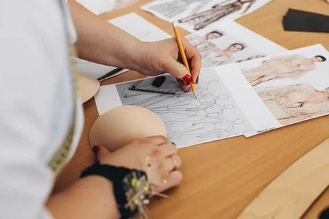 A tailor is drawing some design for future dresses. Stock Photos
