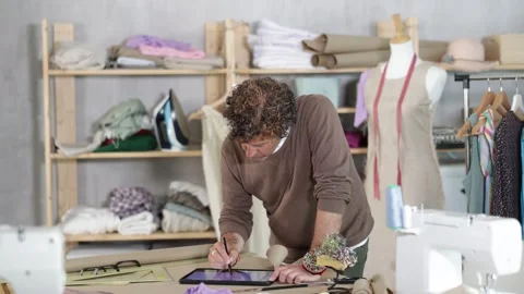 Tailor draws a model of clothes on an electronic tablet. Fashion designer Stock Footage 342128319