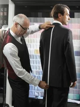 A tailor fitting a man with a suit Stock Photos