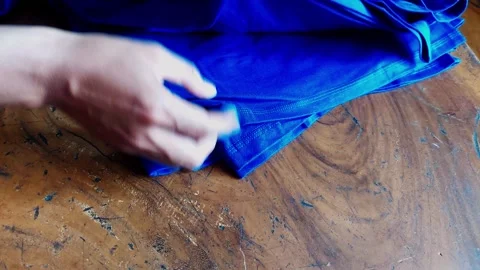 A tailor hands folding and checking the quality of blue fabric t-shirts on .. 스톡 동영상 348376709