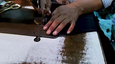Tailor hands stitching fabric on industrial sewing machine in garment workshop Stock Footage 328664710