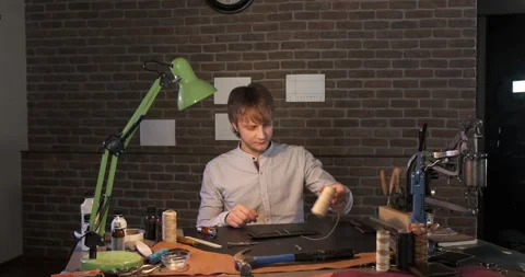 Tailor at His Desktop in Home Workshop Of Leather Products, Man Unwinds Thread Stock Footage 133009115