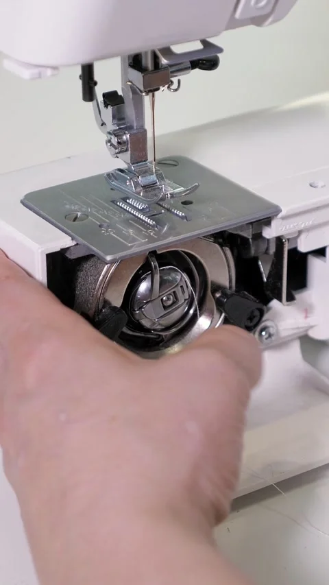 Tailor inserting a bobbin case into a sewing machine, showing the delicate Stock Footage 341432986