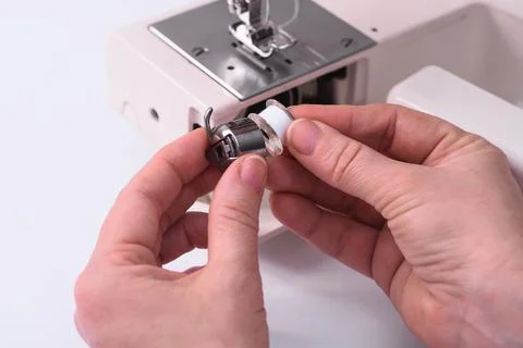 The tailor inserts the babine into the metal spool holder of the sewing machine. 写真素材