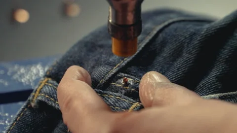 A tailor inserts metal rivets on jeans with a special machine Video stock 221283342