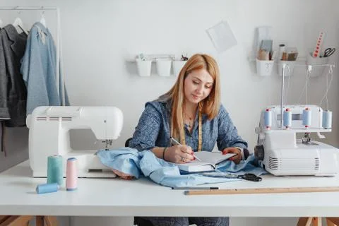 The tailor makes notes in his notebook in a bright studio. Stock Photos