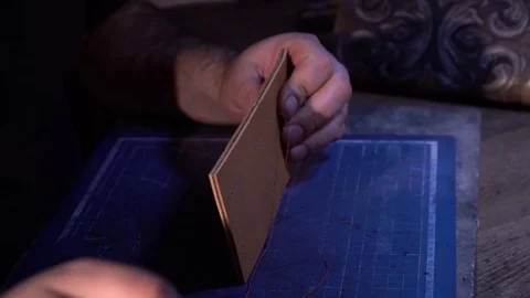 The tailor makes a wallet purse made from hand-made leather in the atelier Stock Footage 85417087