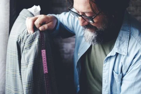 Tailor man at work taking measures on garment in the workshop. Alternative .. Stock Photos