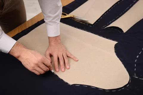 Tailor marking sewing pattern on fabric with chalk at table, closeup Stock Photos