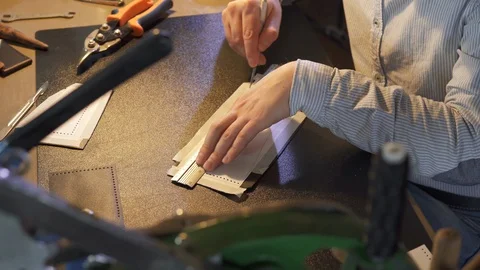 Tailor master works in workshop. Leather craftsman cuts leather. Stock Footage 130145376