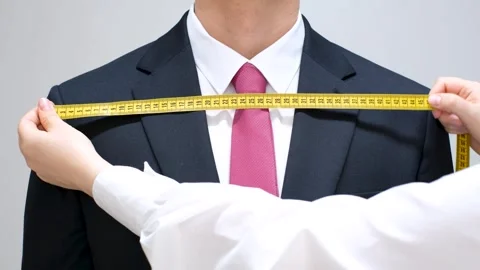 The tailor measures the suit with a measuring tape close-up, front view. Stock Footage 280688117